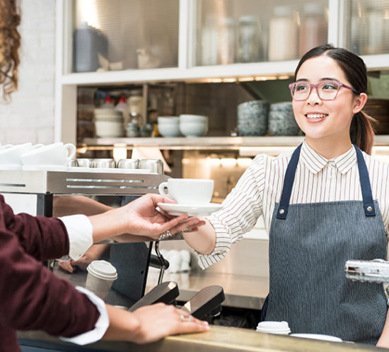 Barista handing over coffee to a customer to promote hospitality insurance by Evalee Insurance Brokers