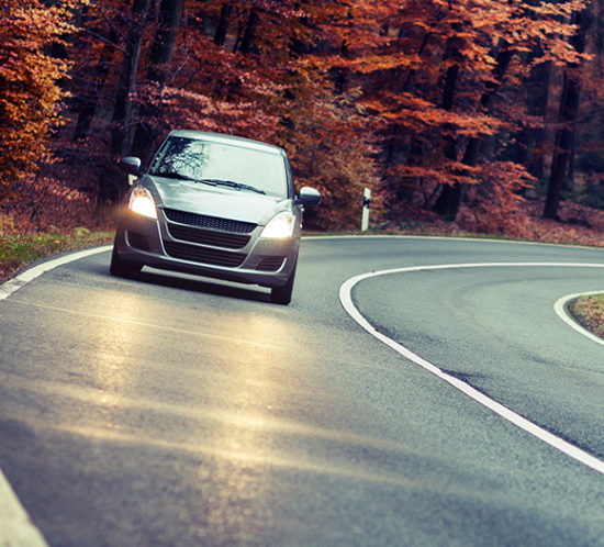 Car driving down quiet road in Autumn to promote car insurance by Evalee Insurance Brokers